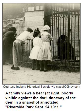 A family views a bear (at right, poorly visible against the dark doorway of the den) in a snapshot annotated "Riverside Park Sept. 24 1911."