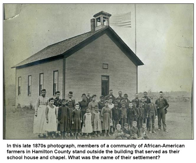 In this late 1870s photograph, members of a community of African-American farmers in Hamilton County stand outside the building that served as their school house and chapel. What was the name of their settlement?