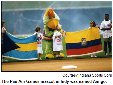 Pan Am Games mascot Amigo holds flags with children at baseball diamond in 1987. Image courtesy Indiana Sports Corp.