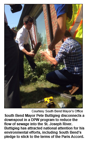 South Bend Mayor Pete Buttigieg disconnects a downspout in a DPW program to reduce the flow of sewage into the St. Joseph River. Buttigieg has attracted national attention for his environmental efforts, including South Bend’s pledge to stick to the terms of the Paris Accord. 
Courtesy South Bend Mayor's Office.