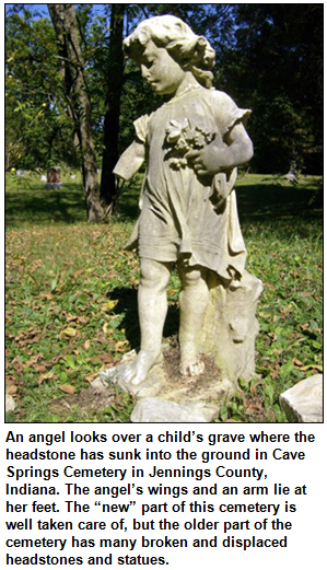 An angel looks over a child’s grave where the headstone has sunk into the ground in Cave Springs Cemetery in Jennings County, Indiana. The angel’s wings and an arm lie at her feet. The “new” part of this cemetery is well taken care of, but the older part of the cemetery has many broken and displaced headstones and statues.