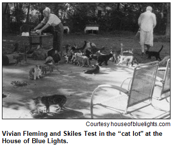 Vivian Fleming and Skiles Test in the “cat lot” at the House of Blue Lights, with dozens of cats milling around their feet.
