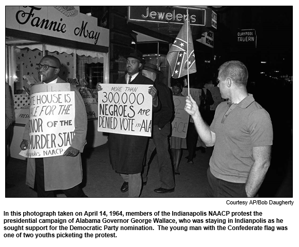 In this photograph taken on April 14, 1964, members of the Indianapolis NAACP protest the presidential campaign of Alabama Governor George Wallace, who was staying in Indianpolis as he sought support for the Democratic Party nomination.  The young man with the Confederate flag was one of two youths picketing the protest.
