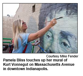 Pamela Bliss touches up her mural of Kurt Vonnegut on Massachusetts Avenue in downtown Indianapolis
