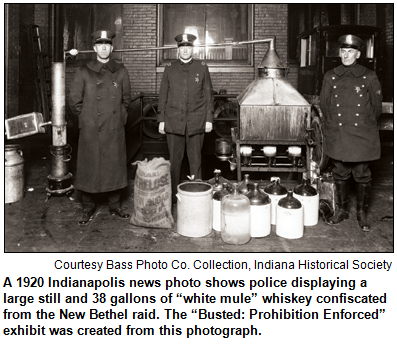 A 1920 Indianapolis news photo shows police displaying a large still and 38 gallons of “white mule” whiskey confiscated from the New Bethel raid. The “Busted: Prohibition Enforced” exhibit was created from this photograph.